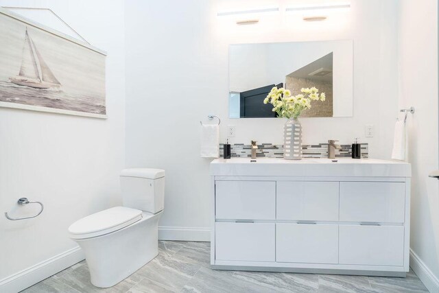 bathroom featuring double vanity, baseboards, and toilet