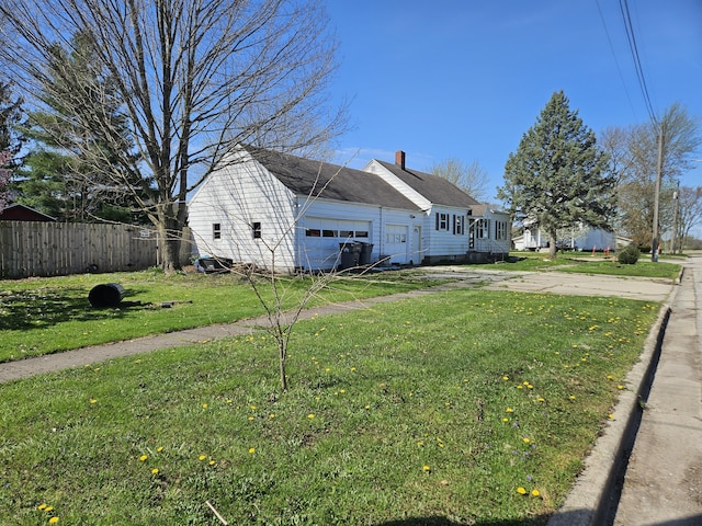 9 W Michigan St, Three Oaks, MI 49128 - view of home's exterior featuring a chimney, an attached garage, fence, driveway, and a lawn