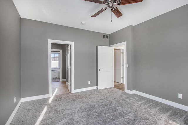 unfurnished bedroom featuring light colored carpet, visible vents, ceiling fan, ensuite bathroom, and baseboards