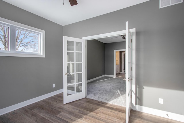 spare room with wood finished floors, baseboards, visible vents, a ceiling fan, and french doors