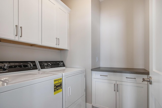 clothes washing area featuring cabinet space and washer and clothes dryer