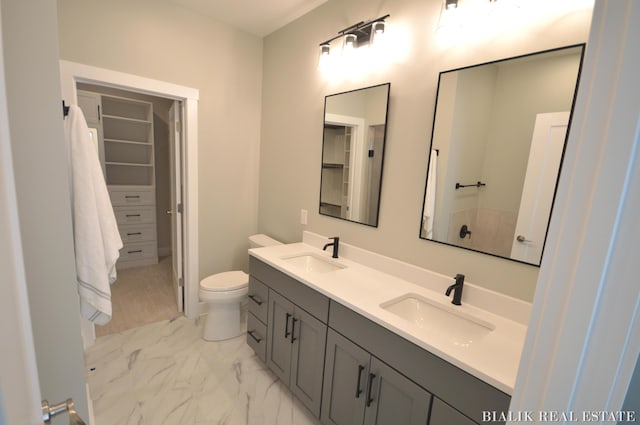 full bath with double vanity, toilet, marble finish floor, and a sink