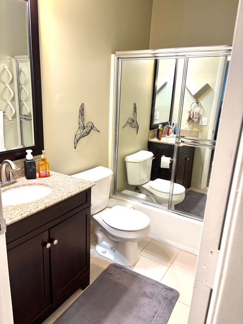 full bathroom featuring tile patterned floors, vanity, toilet, and an enclosed shower