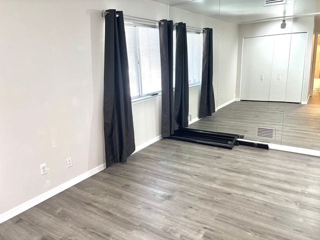 empty room with baseboards, visible vents, and wood finished floors