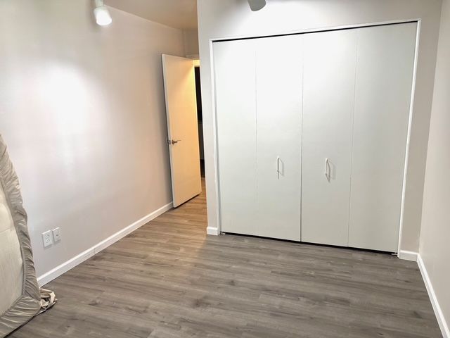 unfurnished bedroom featuring a closet, wood finished floors, and baseboards