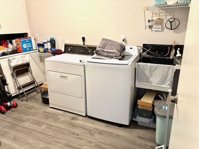washroom featuring washing machine and clothes dryer, light wood-style flooring, laundry area, and a sink