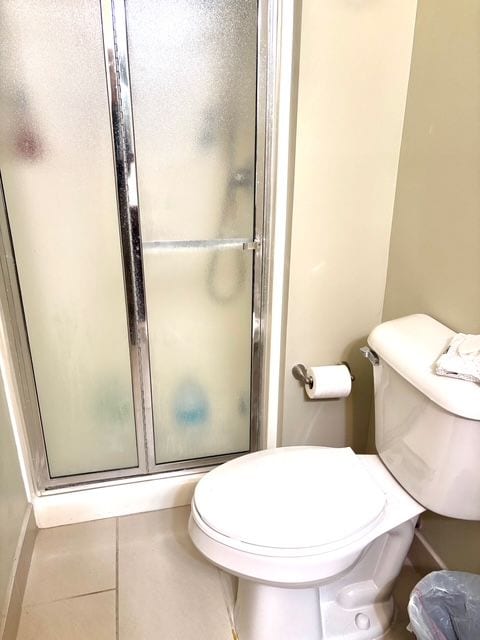 full bathroom with toilet, a stall shower, tile patterned floors, and baseboards