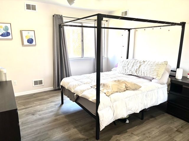 bedroom with visible vents, wood finished floors, and baseboards