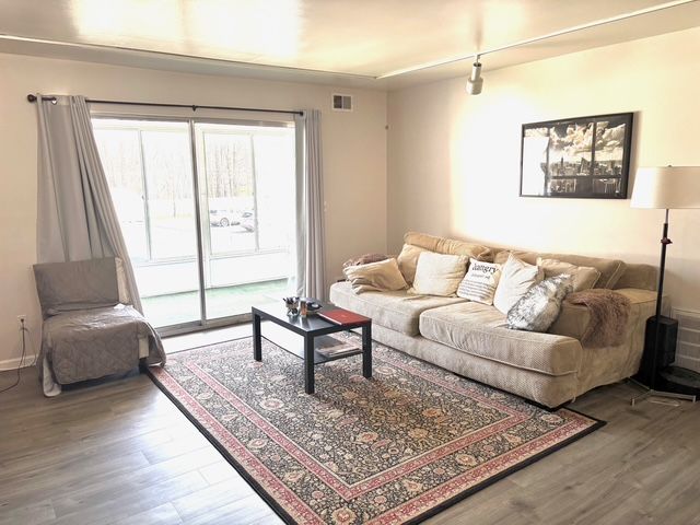 living area featuring visible vents and wood finished floors