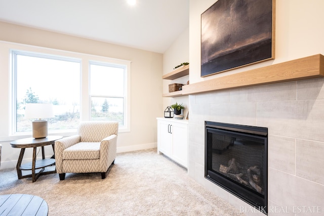 sitting room featuring a tiled fireplace, light carpet, and baseboards