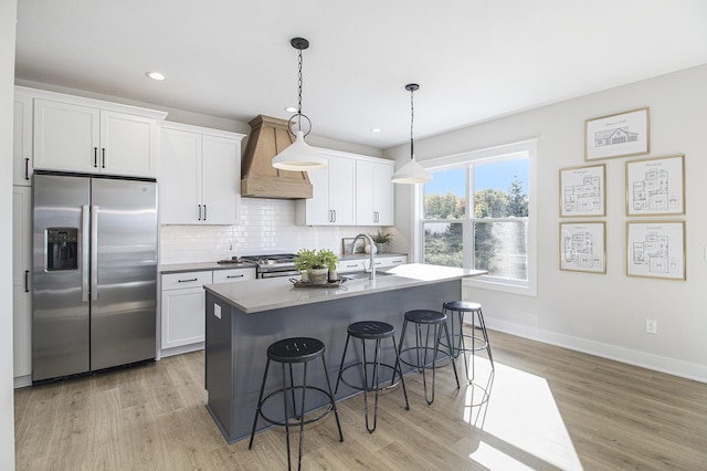 kitchen featuring a kitchen bar, custom range hood, white cabinetry, and stainless steel appliances