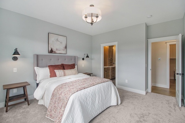 bedroom featuring baseboards, light carpet, and ensuite bathroom