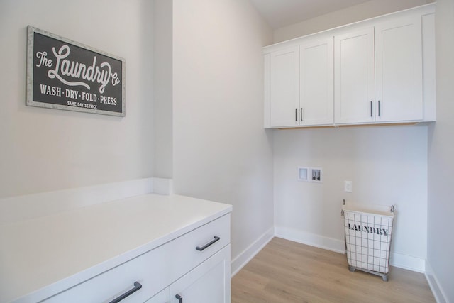clothes washing area featuring hookup for a washing machine, light wood-style flooring, cabinet space, and baseboards