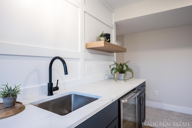 kitchen with a sink, light stone counters, light carpet, and beverage cooler