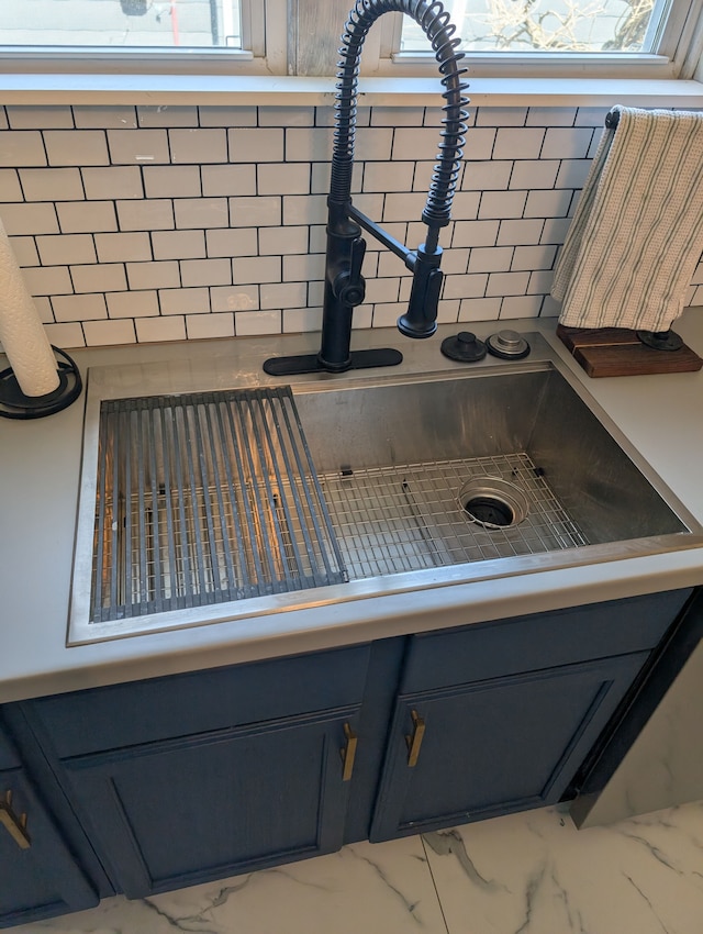 interior details with gray cabinetry, a sink, and light countertops