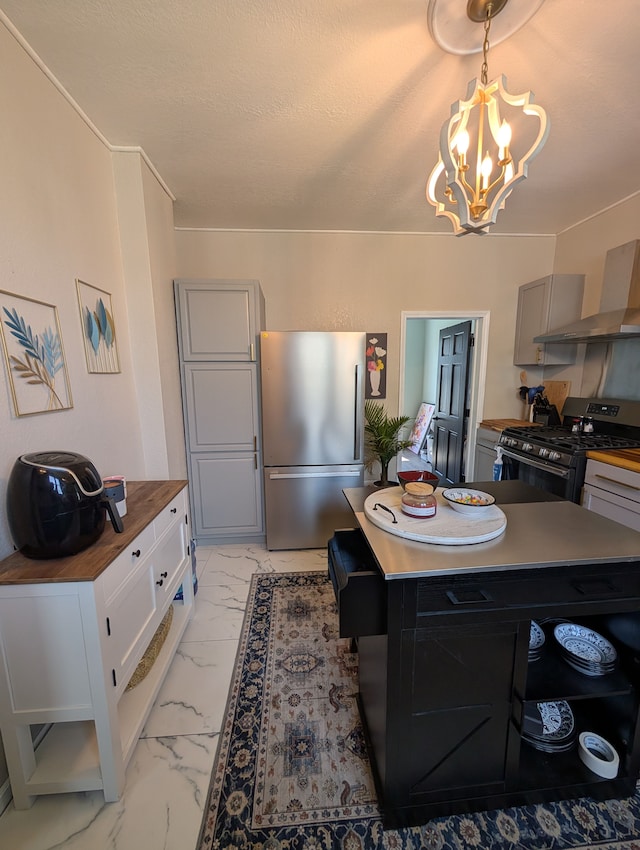 kitchen featuring an inviting chandelier, gray cabinets, wall chimney exhaust hood, appliances with stainless steel finishes, and butcher block counters