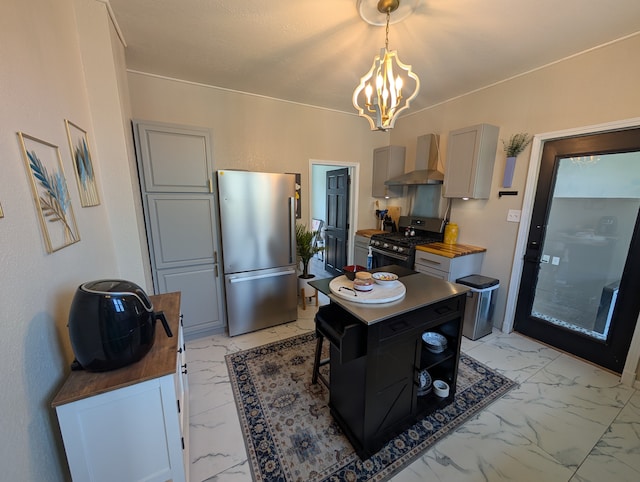 kitchen featuring appliances with stainless steel finishes, marble finish floor, gray cabinetry, a notable chandelier, and wall chimney exhaust hood