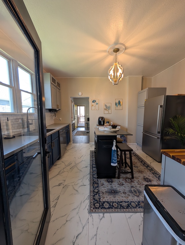 kitchen featuring tasteful backsplash, freestanding refrigerator, a chandelier, decorative light fixtures, and dishwasher