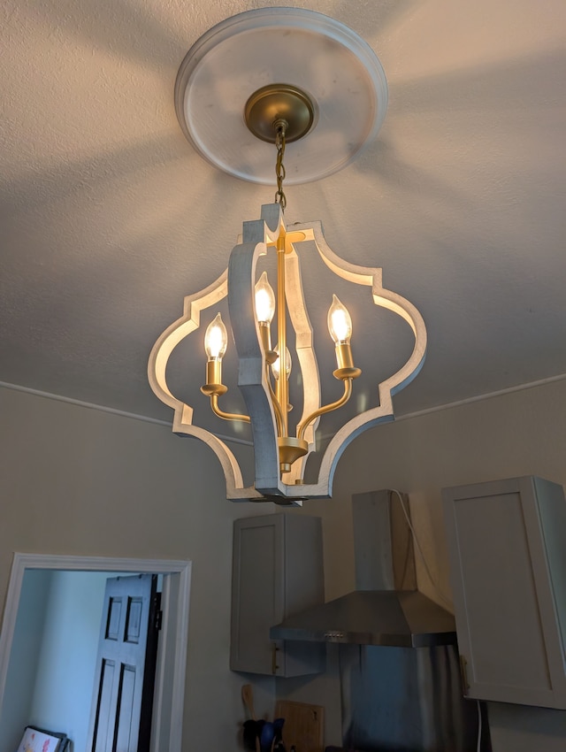 interior details featuring a chandelier and wall chimney range hood