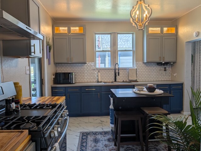 kitchen with blue cabinetry, extractor fan, gas range, and a sink