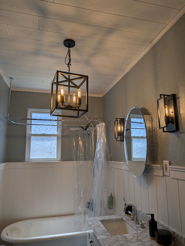 interior details with crown molding, a textured wall, a wainscoted wall, an inviting chandelier, and shower / bath combination with curtain
