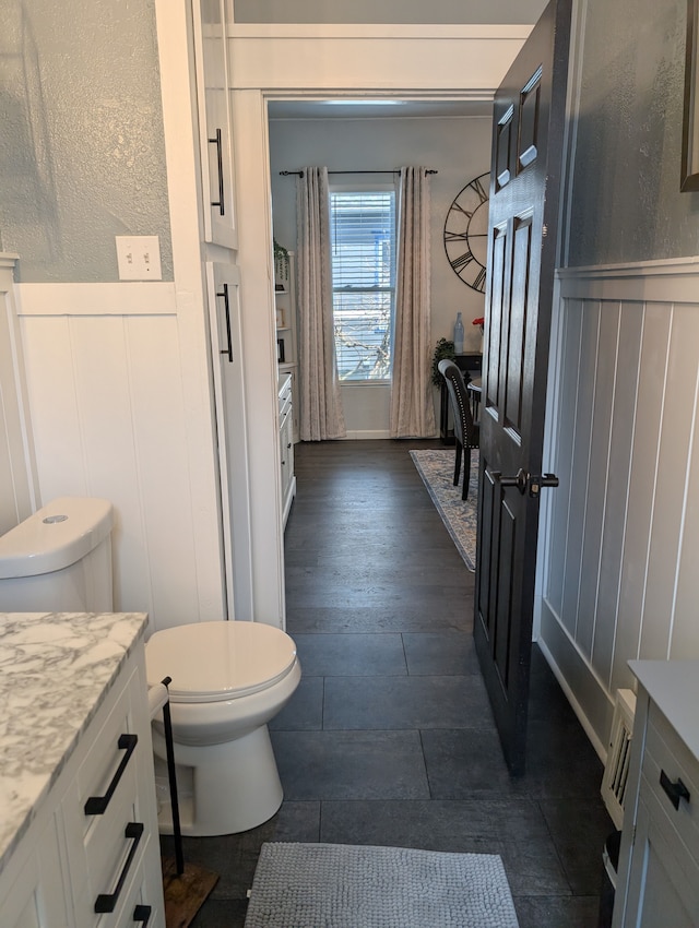 1204 Stanton St, Bay City, MI 48708 - bathroom with toilet, a decorative wall, vanity, and a wainscoted wall