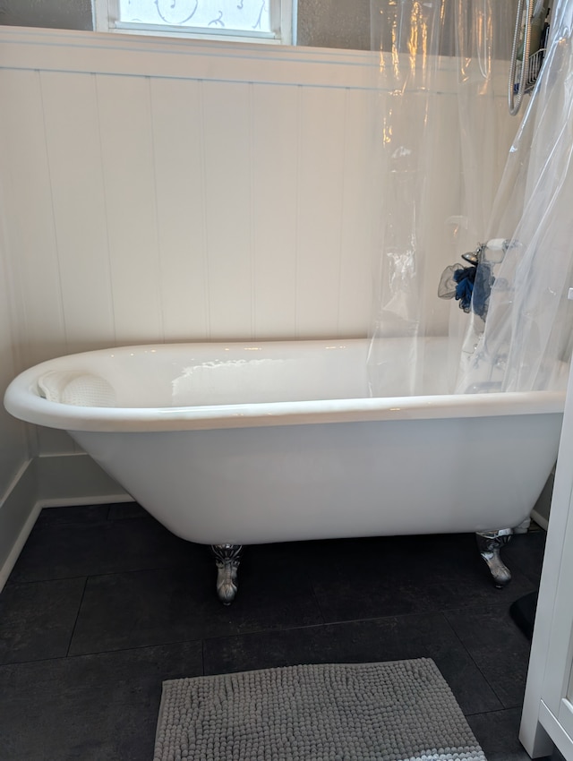 bathroom featuring a soaking tub, baseboards, and tile patterned floors