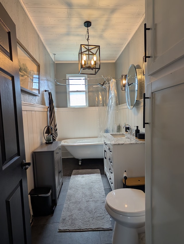 bathroom with vanity, toilet, a wainscoted wall, a freestanding bath, and a shower with shower curtain