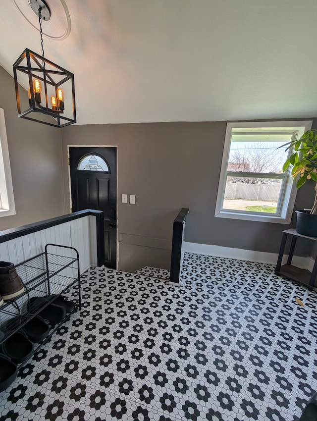 entrance foyer featuring a notable chandelier, carpet, and baseboards