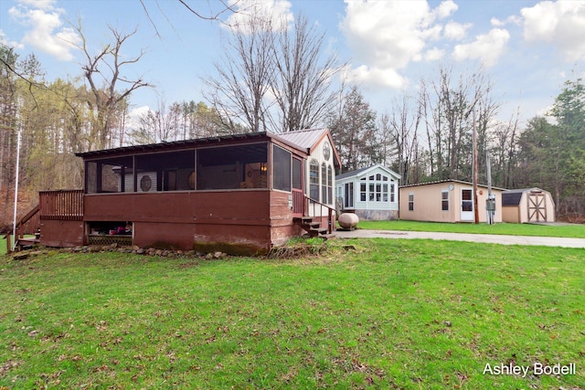 exterior space featuring an outdoor structure, a storage unit, metal roof, a front yard, and a sunroom