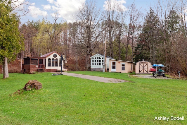view of yard with an outdoor structure, a shed, and a sunroom