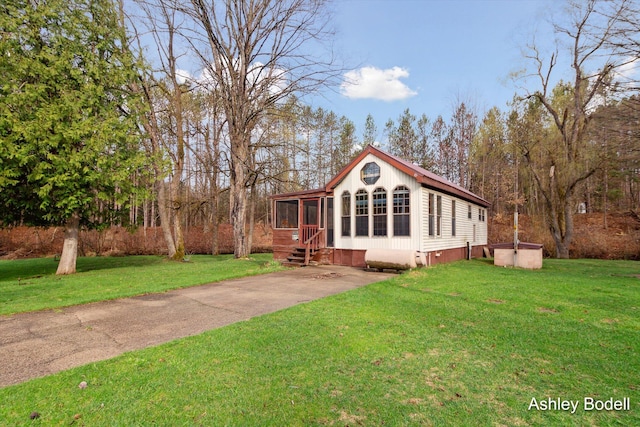 view of front of home featuring driveway, a front yard, crawl space, and a sunroom