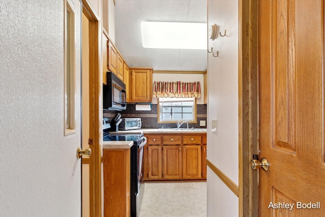 kitchen featuring brown cabinets, stainless steel electric range oven, tasteful backsplash, black microwave, and light countertops