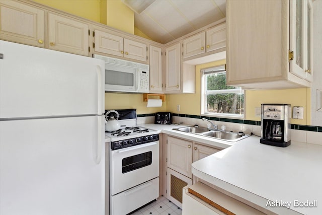 kitchen with a sink, light countertops, vaulted ceiling, light floors, and white appliances