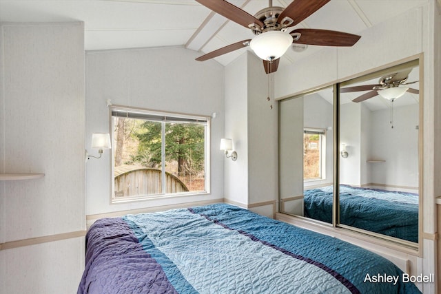 bedroom featuring a ceiling fan, multiple windows, and vaulted ceiling with beams