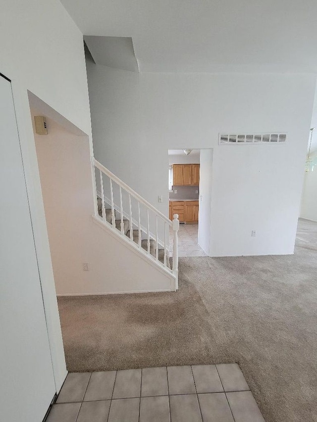 stairway with carpet, visible vents, and tile patterned flooring