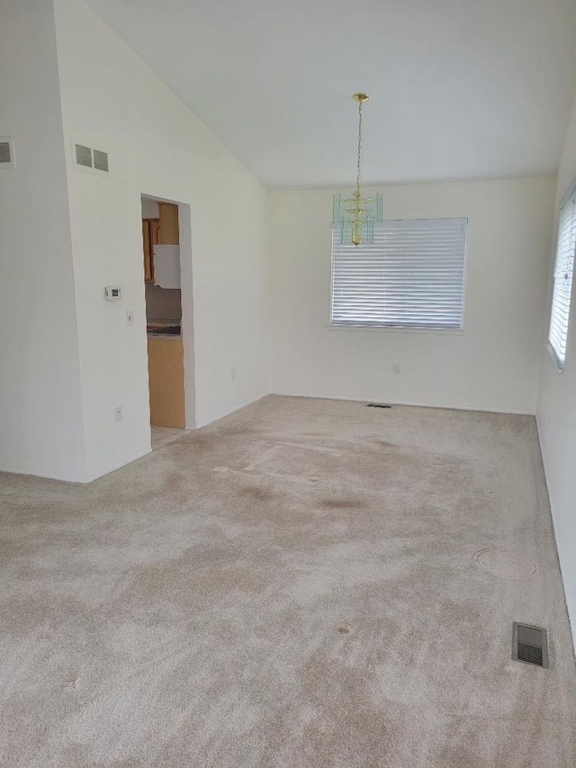 empty room with visible vents, carpet, and vaulted ceiling