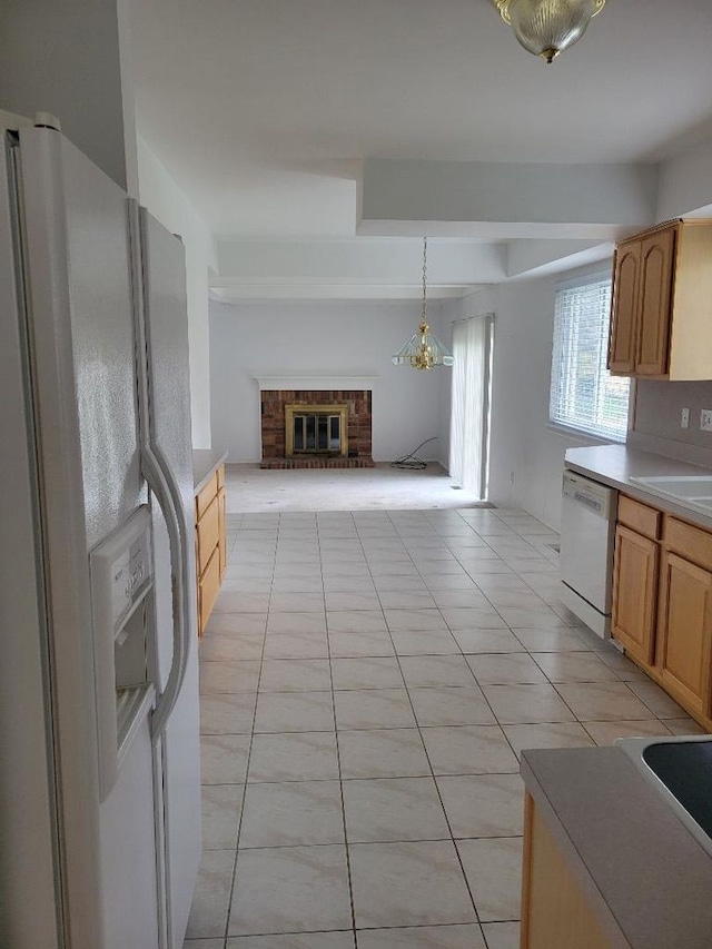 kitchen with light tile patterned floors, a brick fireplace, white appliances, light countertops, and open floor plan