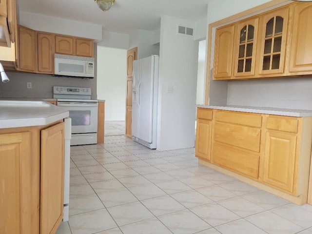 kitchen with glass insert cabinets, a sink, visible vents, light countertops, and white appliances