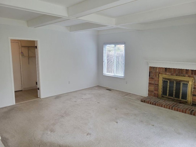 unfurnished living room with carpet flooring, beamed ceiling, and a brick fireplace