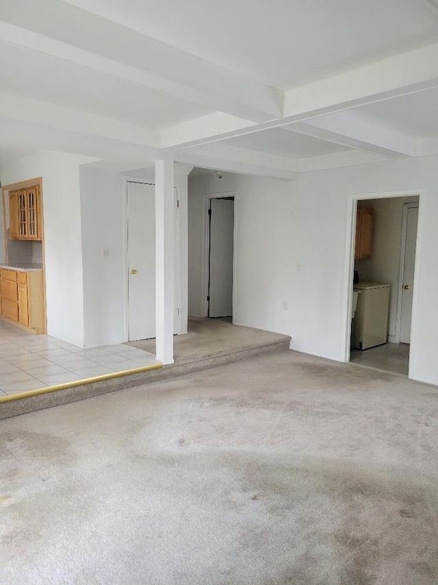 spare room featuring light colored carpet, beam ceiling, and washer / dryer
