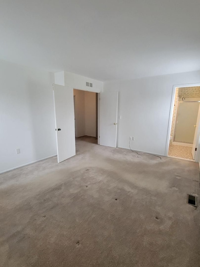 spare room featuring visible vents and light colored carpet