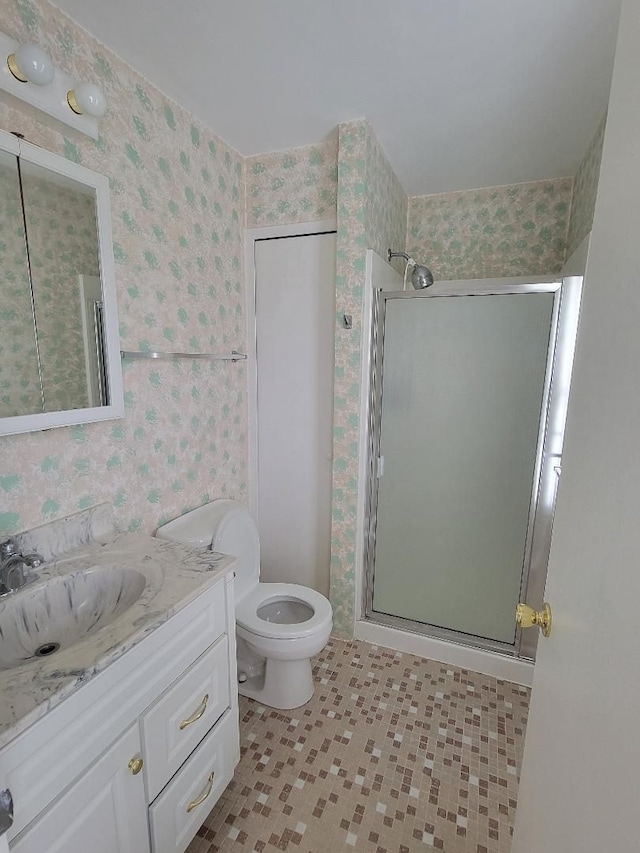 full bathroom featuring wallpapered walls, a shower stall, toilet, and vanity