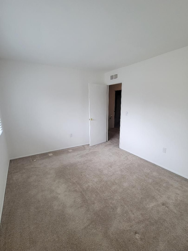carpeted spare room featuring visible vents and baseboards