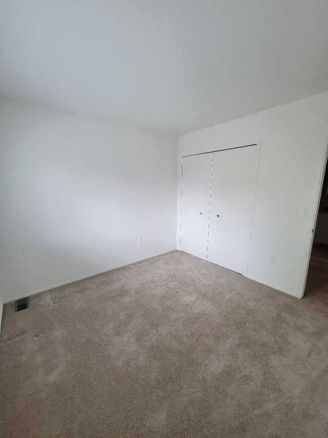 unfurnished bedroom featuring a closet, carpet flooring, and visible vents