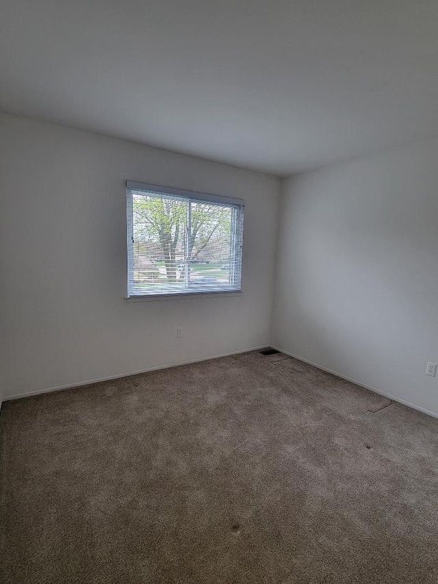 empty room featuring baseboards and carpet flooring