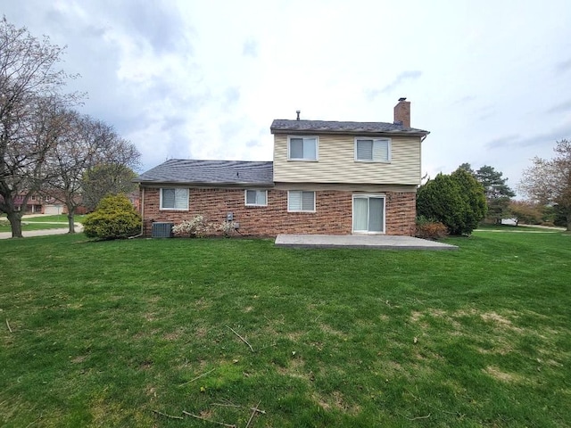 back of house featuring a patio area, a yard, a chimney, central AC, and brick siding