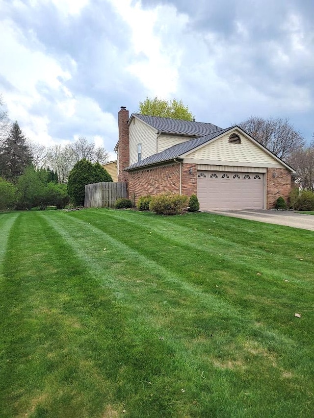 view of side of home featuring a chimney, a yard, fence, a garage, and driveway
