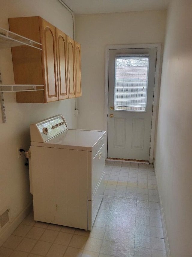 clothes washing area with washer / dryer, cabinet space, and baseboards