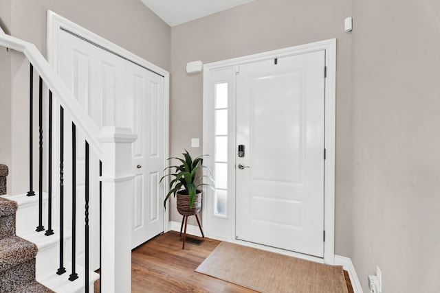foyer entrance featuring stairs, baseboards, and wood finished floors